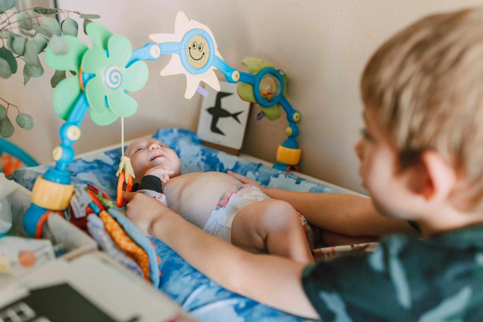 A cute baby lying in a crib, engaged with colorful hanging toys, depicting joyful childhood moments.
