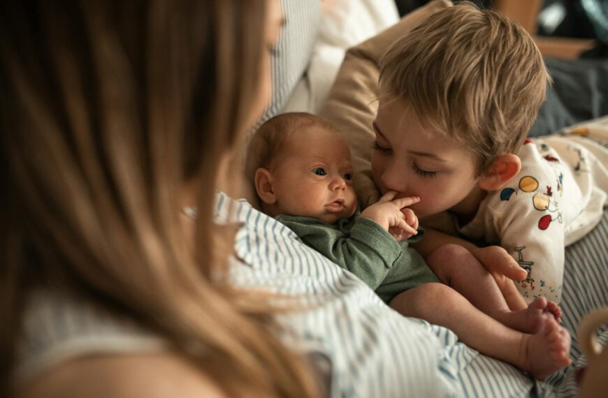 A heartwarming moment as a young child embraces a newborn sibling with mother nearby.