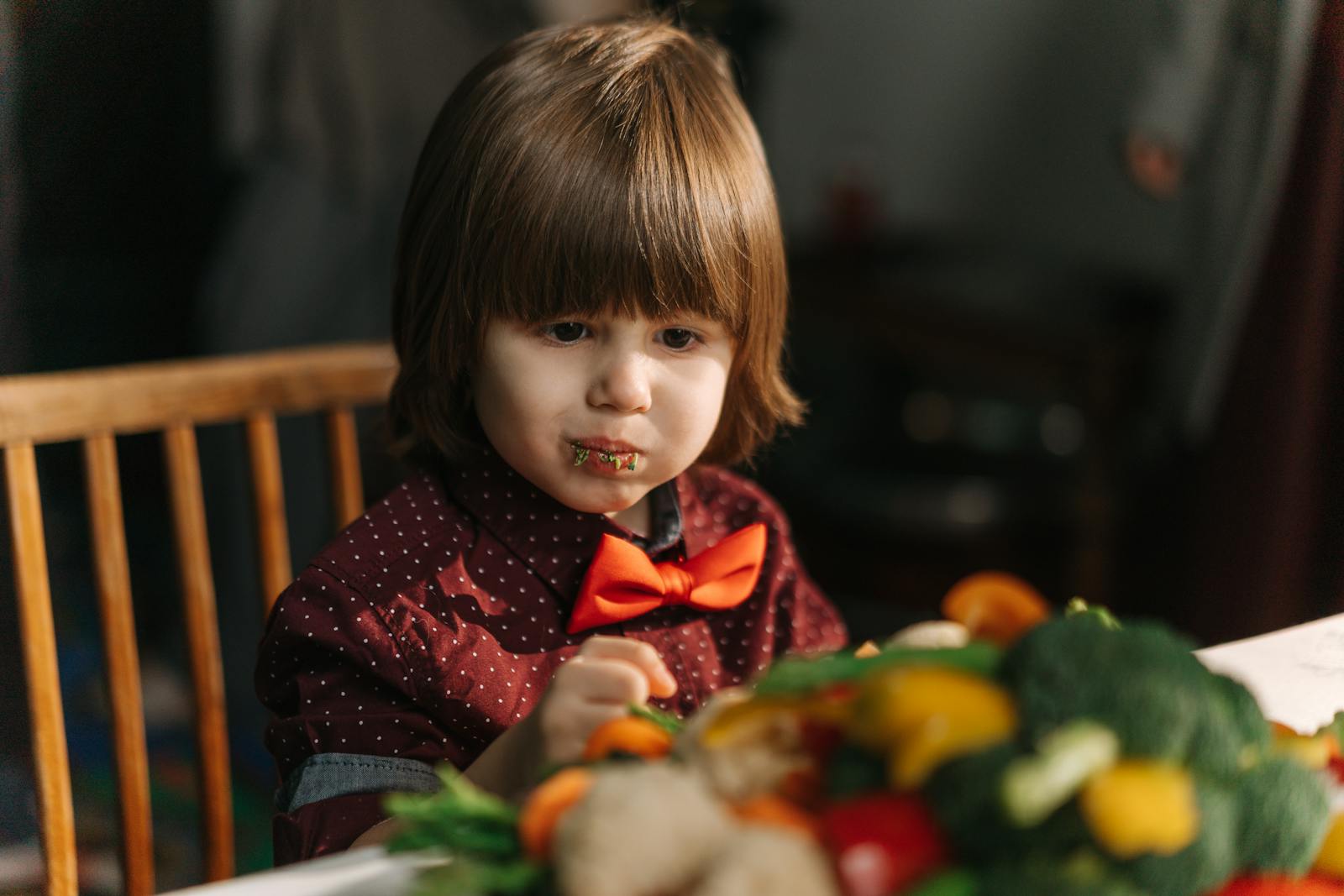 Adorable child enjoying fresh vegetables at the dinner table.