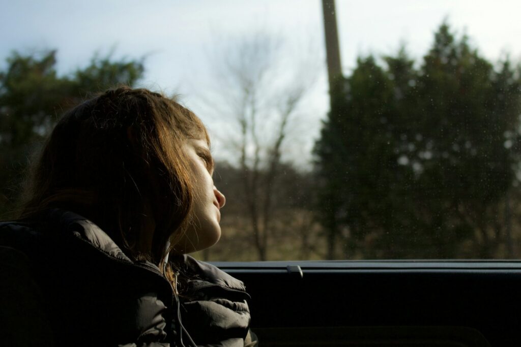 a young girl sitting in a car looking out the window