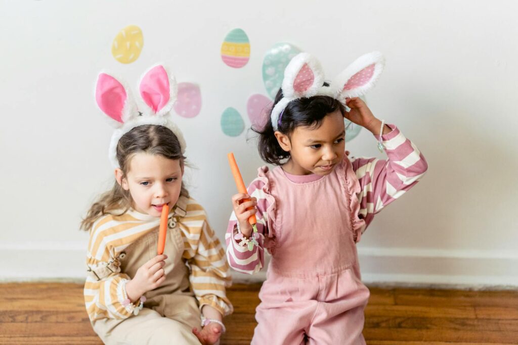 Two children wearing bunny ears enjoy Easter treats indoors, adding festive fun.