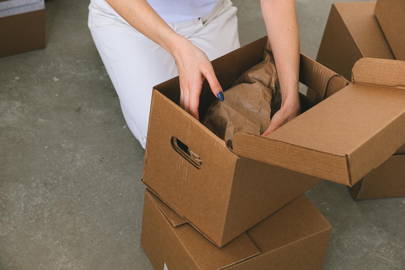 A woman organizing cardboard boxes while preparing to move into a new apartment.