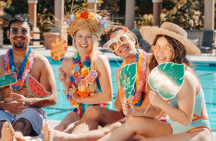 Group of friends enjoying a summer pool party with festive hats and props, celebrating togetherness.