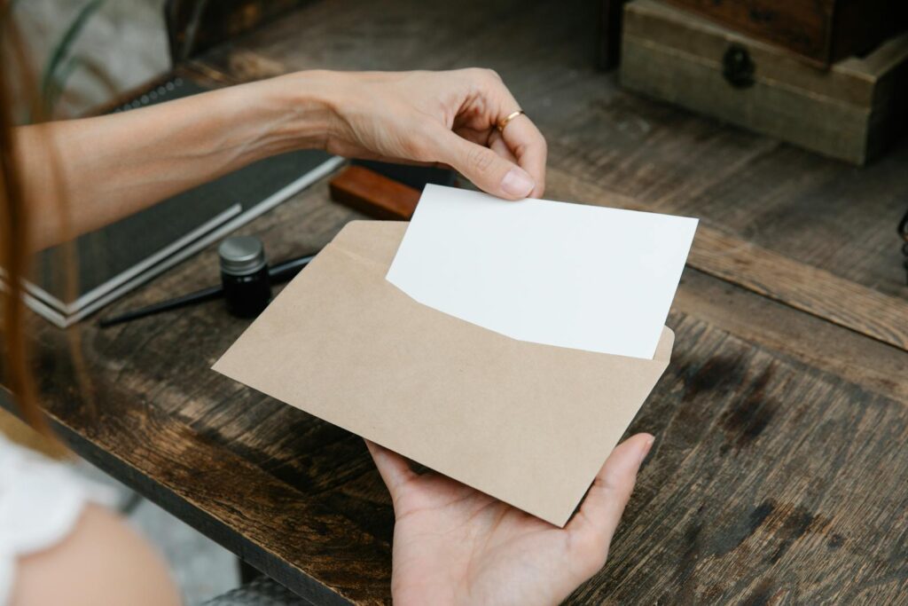 Close-up of hands holding an envelope with a letter on a rustic wooden desk, ideal for communication themes.