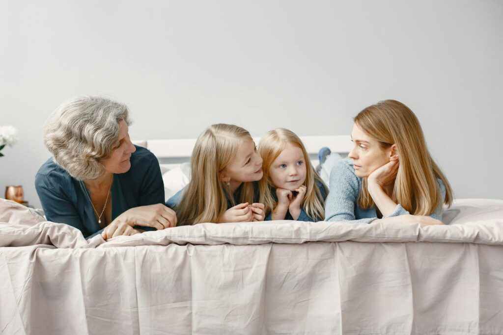 A happy family scene with grandmother, mother, and daughters bonding indoors.