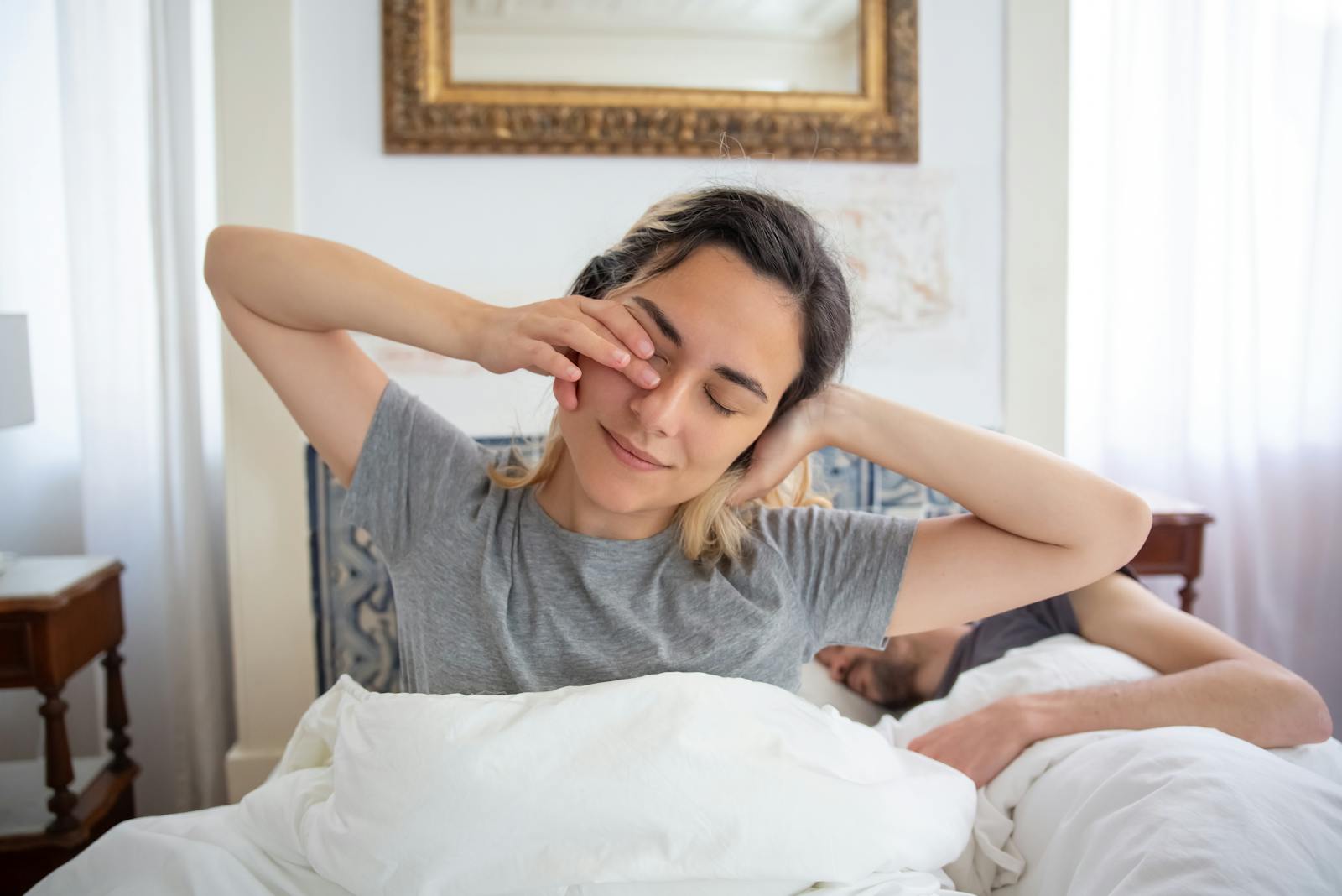 Young woman waking up with a morning stretch, captured indoors with natural light.