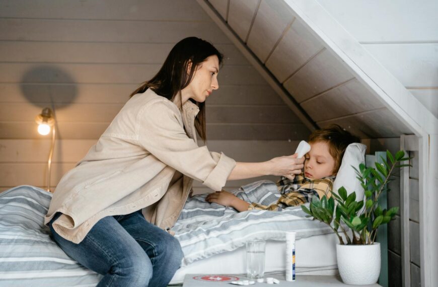 A mother checks her sick child's temperature in a cozy bedroom setting, showcasing care and parenting.