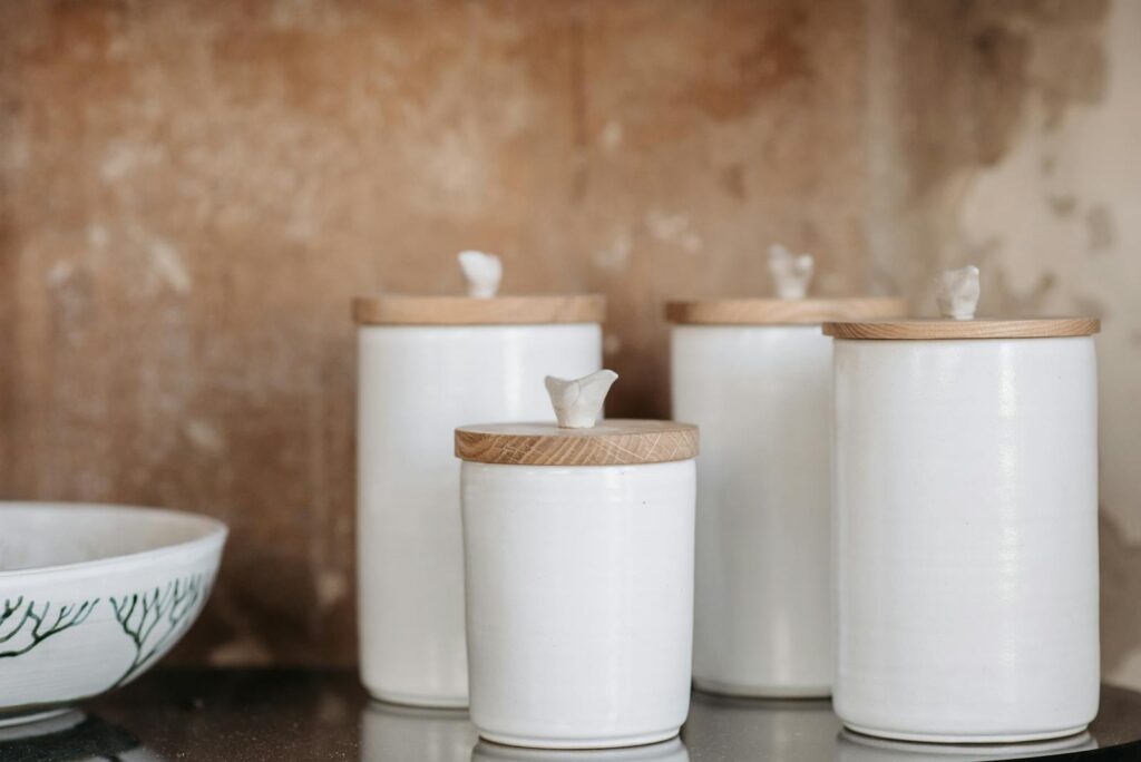 Stylish white ceramic canisters with wooden lids for modern kitchen storage aesthetics.