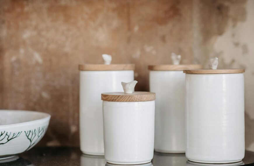 Stylish white ceramic canisters with wooden lids for modern kitchen storage aesthetics.