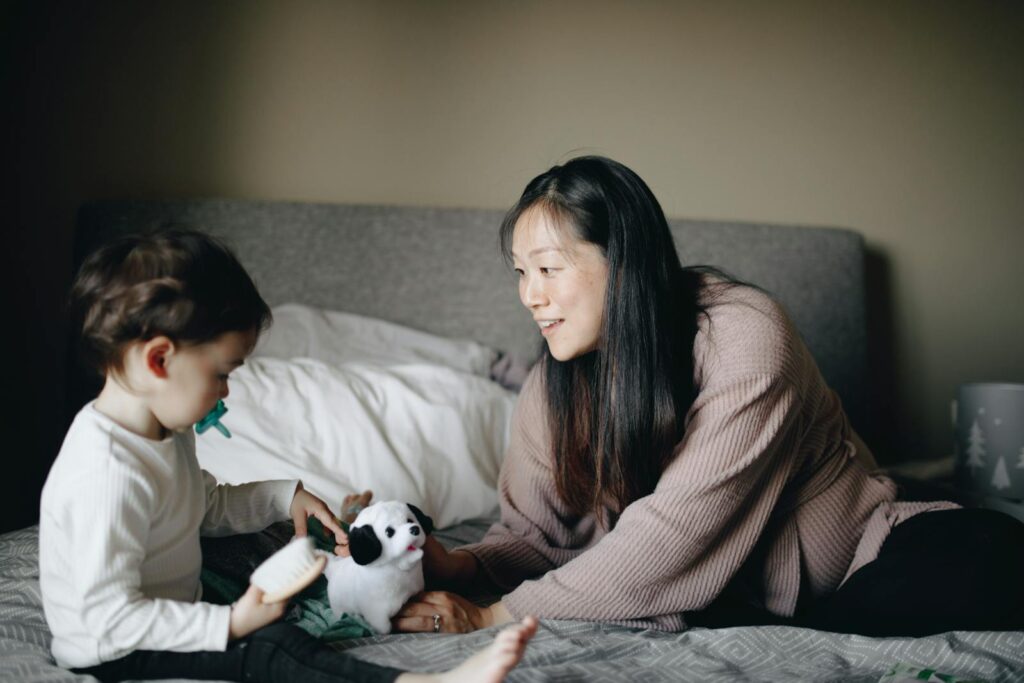 A heartwarming scene of a mother and child playing with toys on a bed. Captures the essence of family bonding.