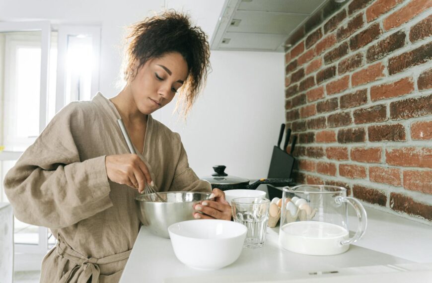 A woman cooking with ingredients in a contemporary kitchen setting.