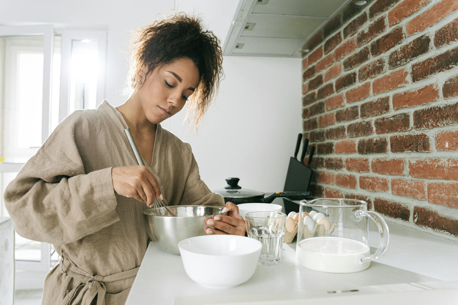 A woman cooking with ingredients in a contemporary kitchen setting.