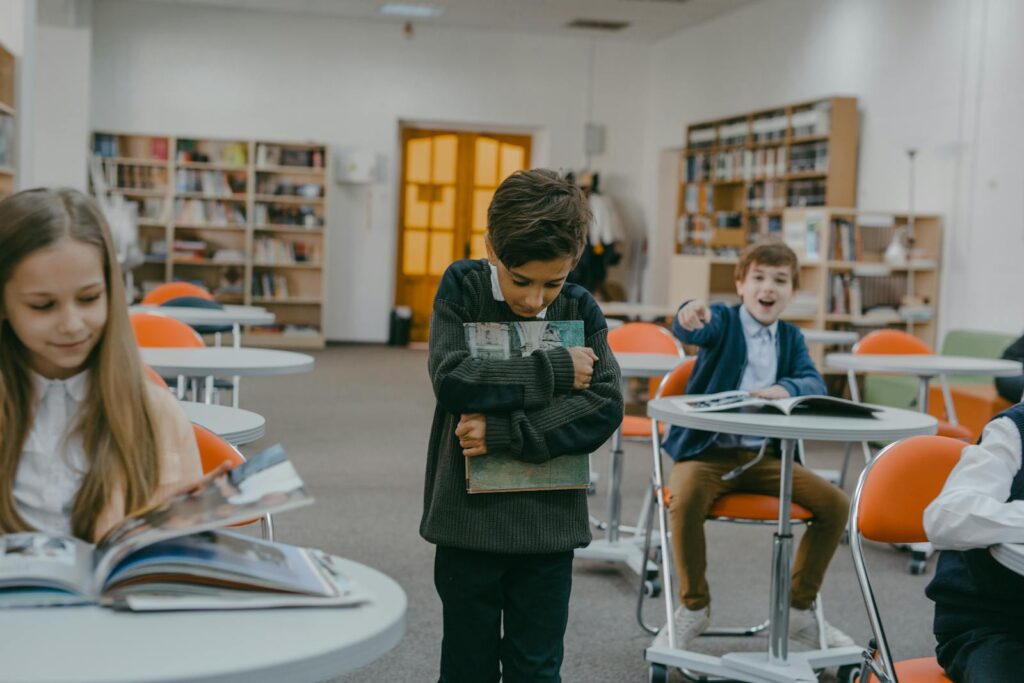A boy being bullied by classmates in a school classroom setting.
