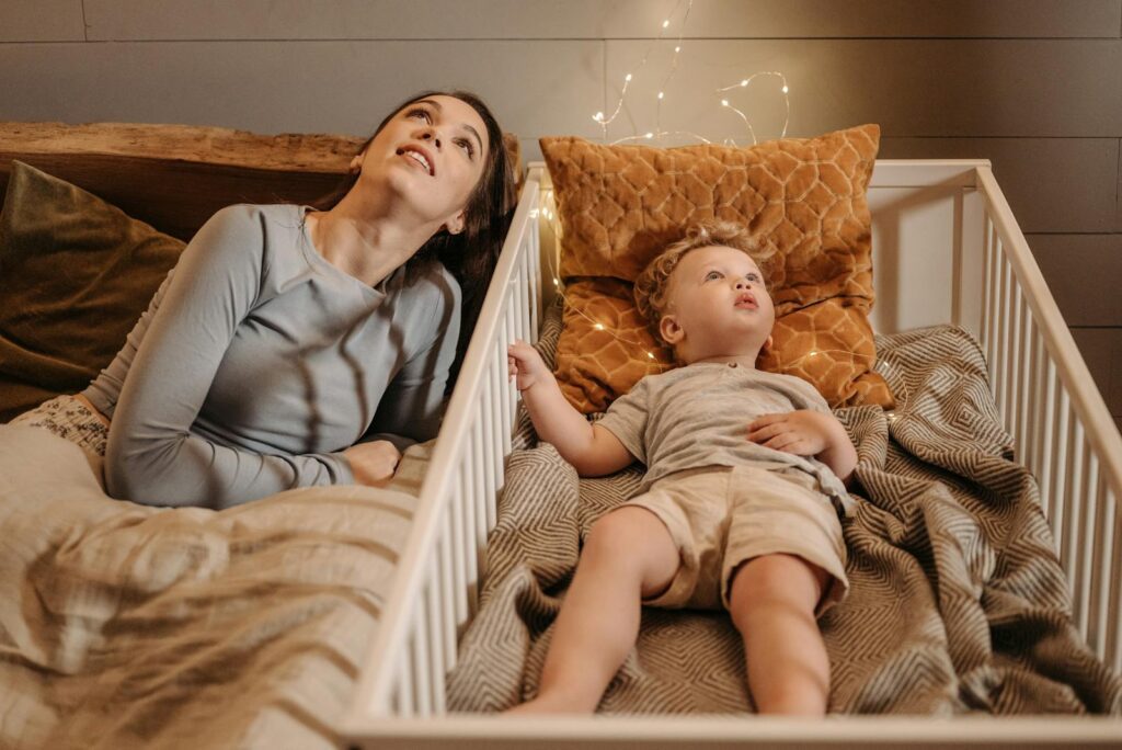 A mother and her toddler relax in a cozy, softly-lit bedroom, creating a warm family moment.