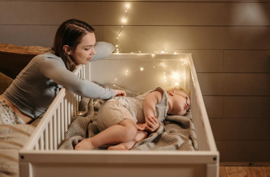 A tender moment of a mother watching over her sleeping baby in a warmly lit bedroom.