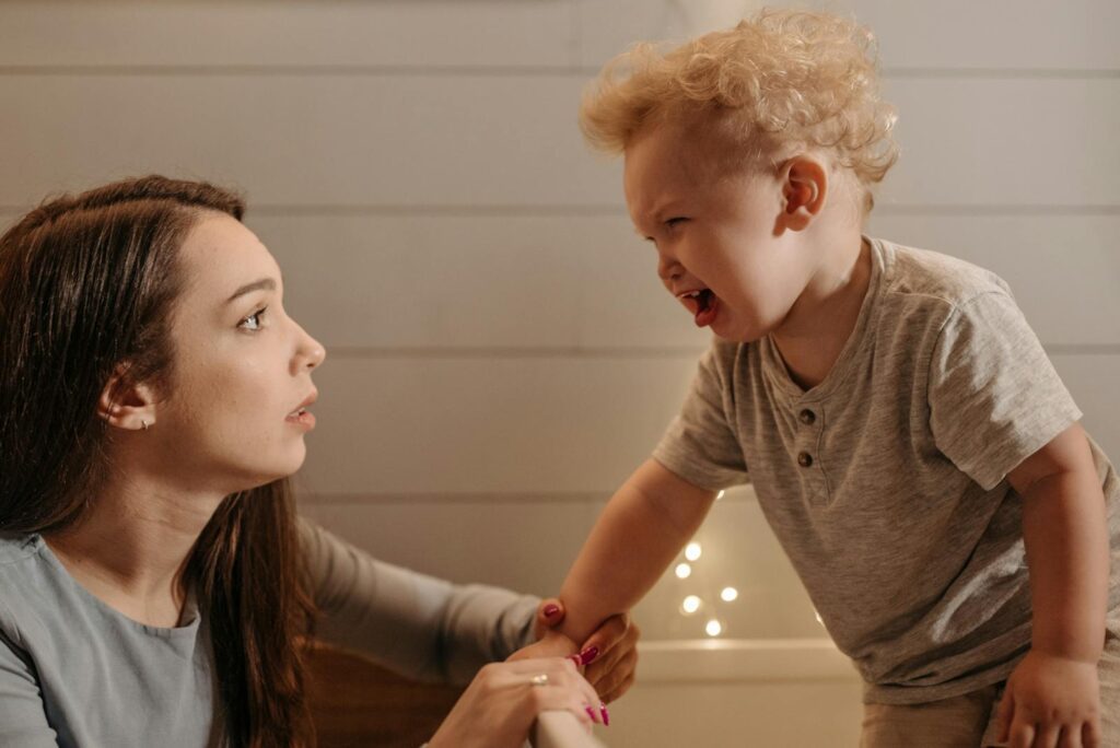 A mother and son share a moment in a cozy, warmly lit bedroom.