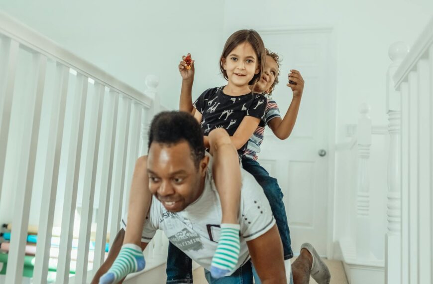 Father playing with children in hallway, piggyback ride fun.
