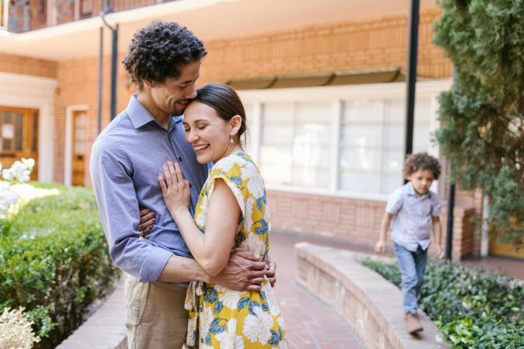 A joyful family embracing outdoors, capturing warmth and togetherness with a young child nearby.