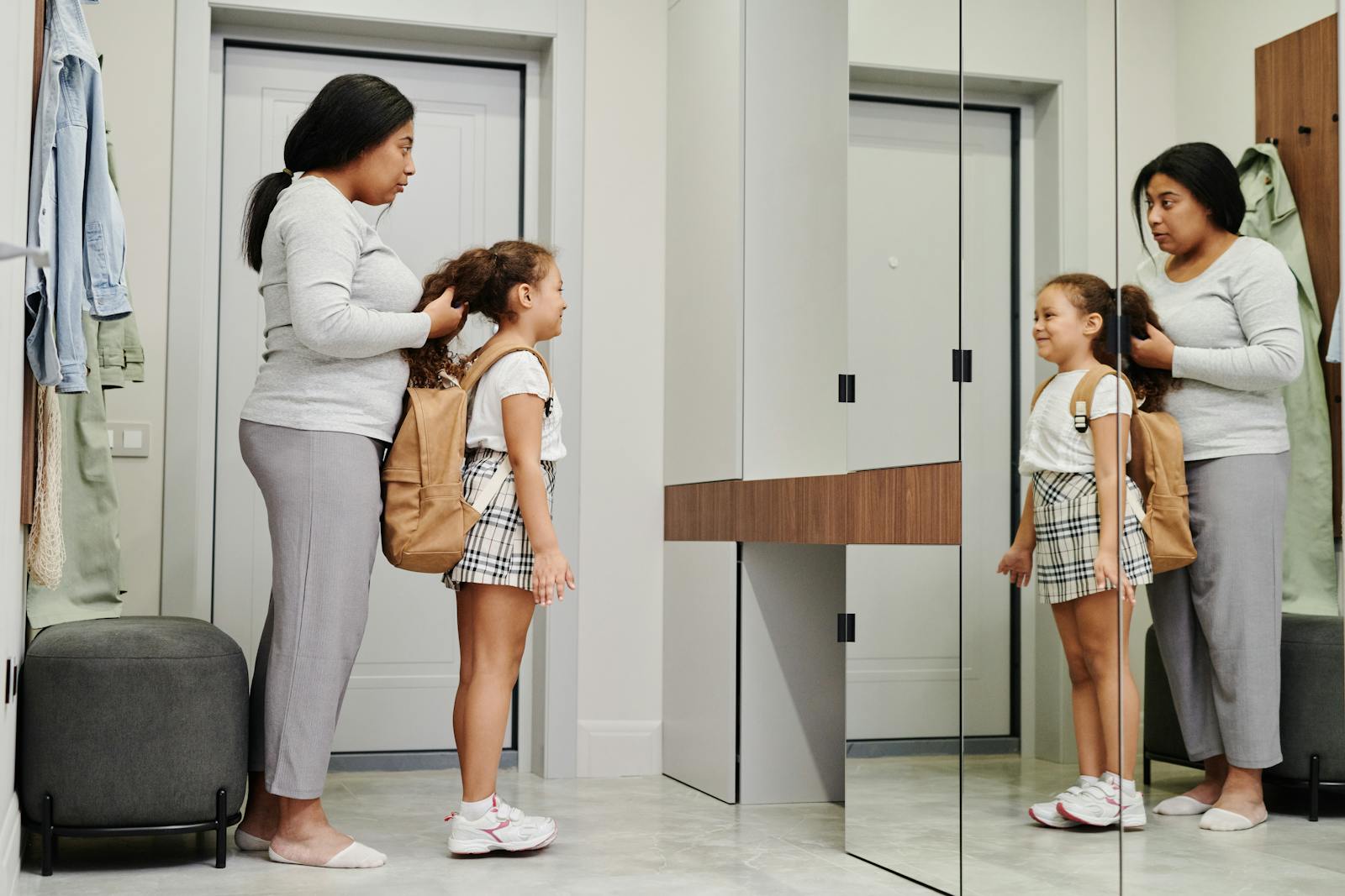 A mother and daughter preparing for school in front of a mirror, showcasing morning routines.