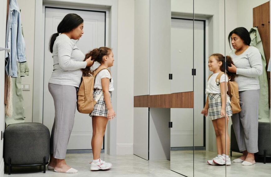 A mother and daughter preparing for school in front of a mirror, showcasing morning routines.