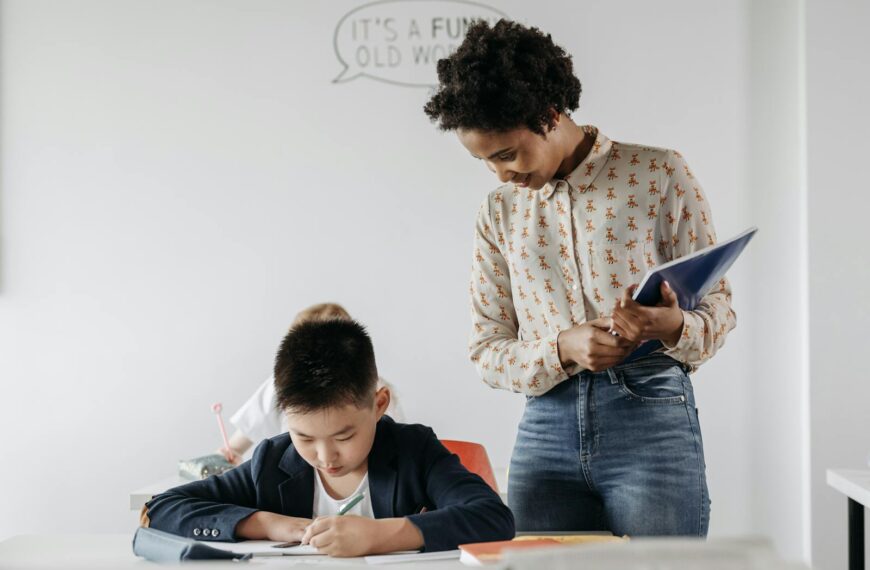 A teacher guides a student in a classroom, fostering an environment of learning and support.