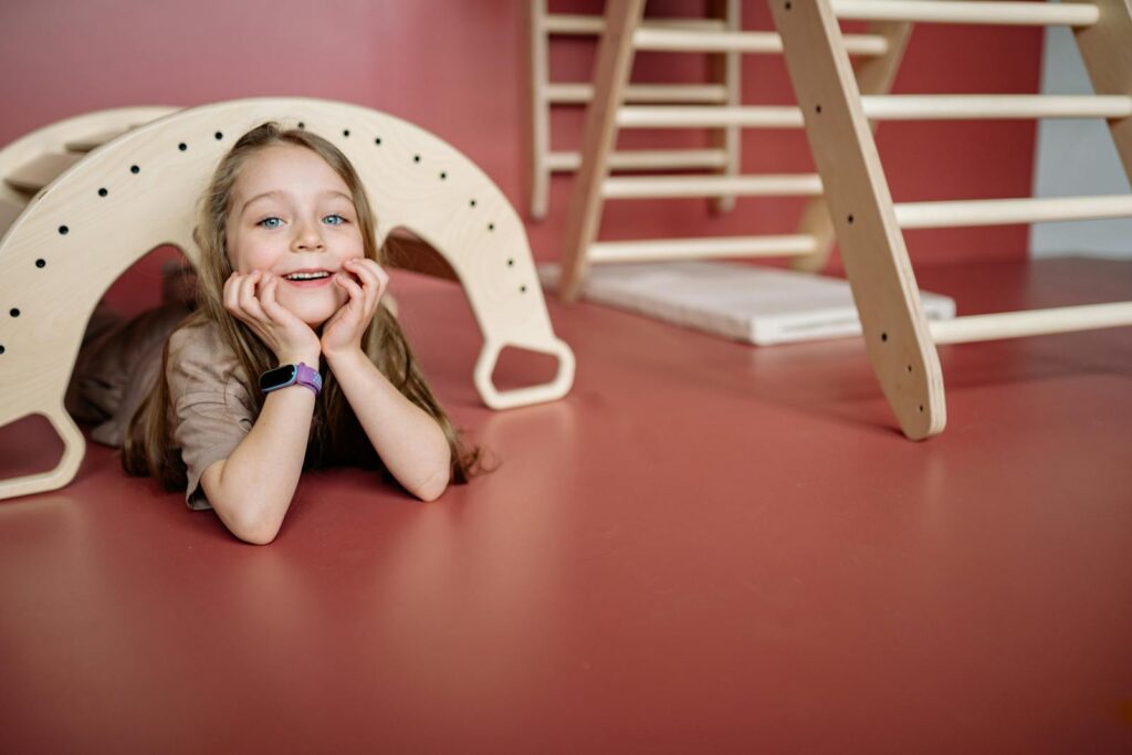 A joyful child playing with a wooden toy bridge indoors, smiling and having fun.