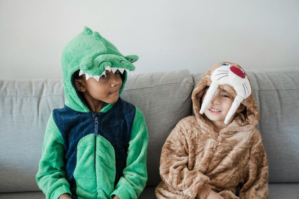 Two boys in animal costumes sitting together on a sofa indoors.