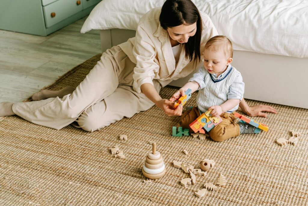 Mother and baby engaging in play with colorful wooden toys on a cozy day indoors.