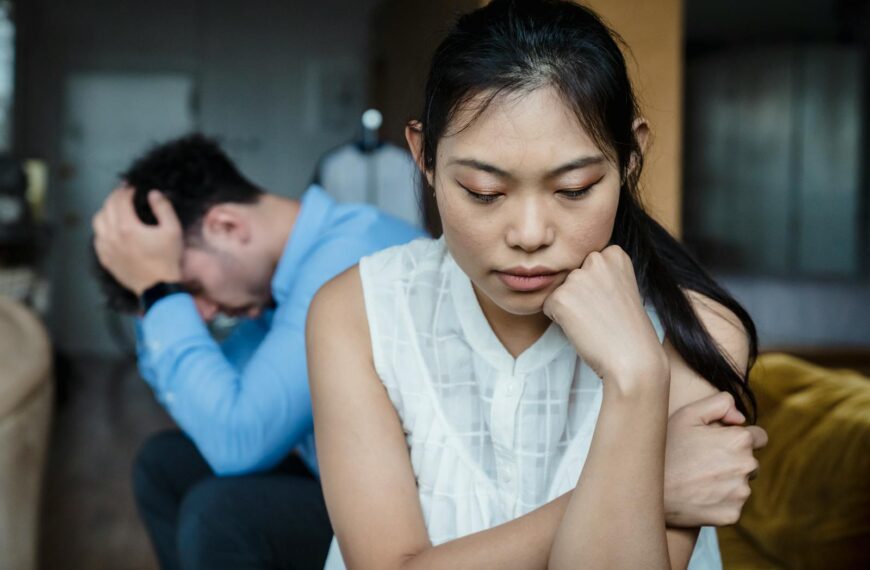 A couple experiencing relationship tension sitting silently on a sofa.
