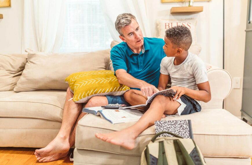 A father and son bonding over books in a cozy living room setting.