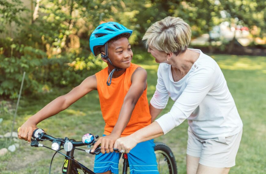 A joyful moment between a mother and son learning to ride a bike in a sunny park.