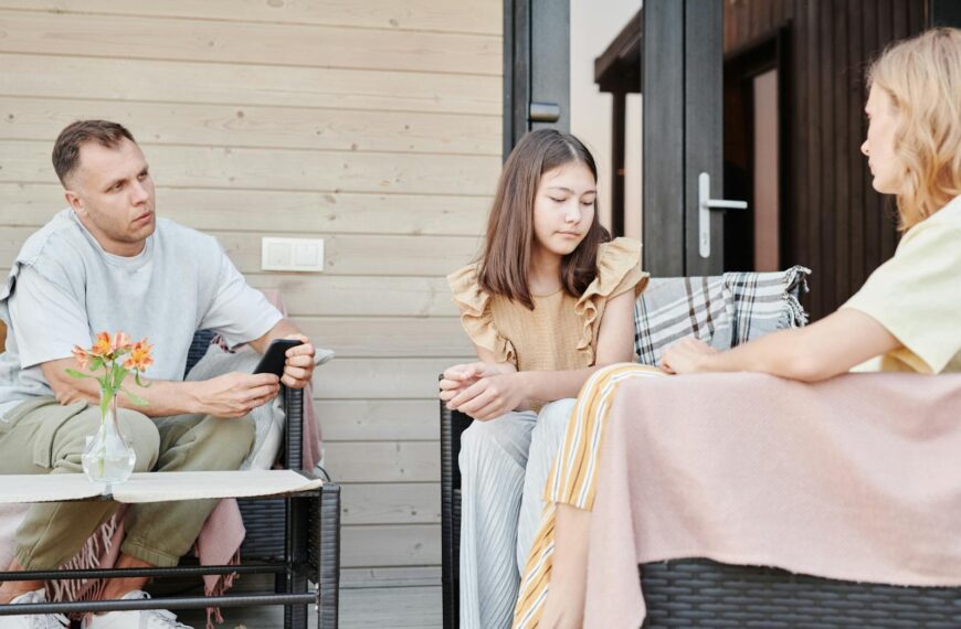 A family of three having a serious conversation outdoors on a patio.