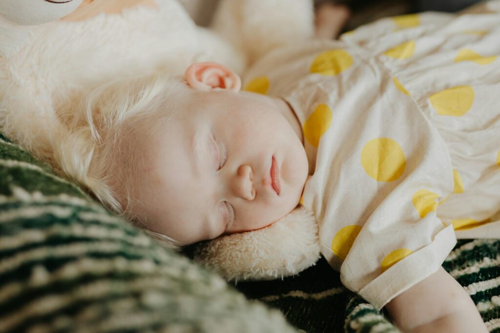 A serene image of a baby in a yellow polka dot dress sleeping peacefully indoors.