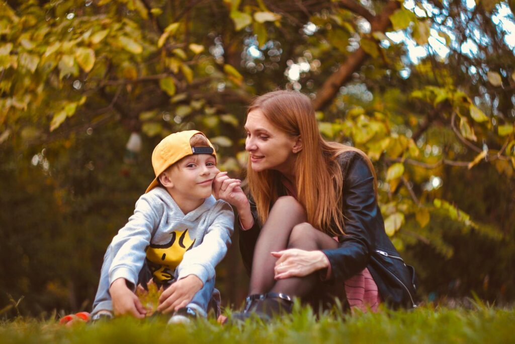 Mother and son enjoying playful moment outdoors in a lush green park.
