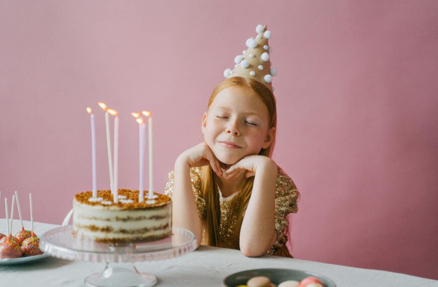 A young girl celebrating her birthday with a cake, wearing a festive party hat.