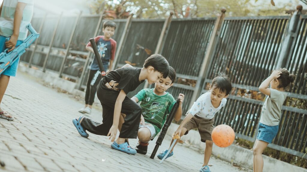 Children play together with a ball and sticks.