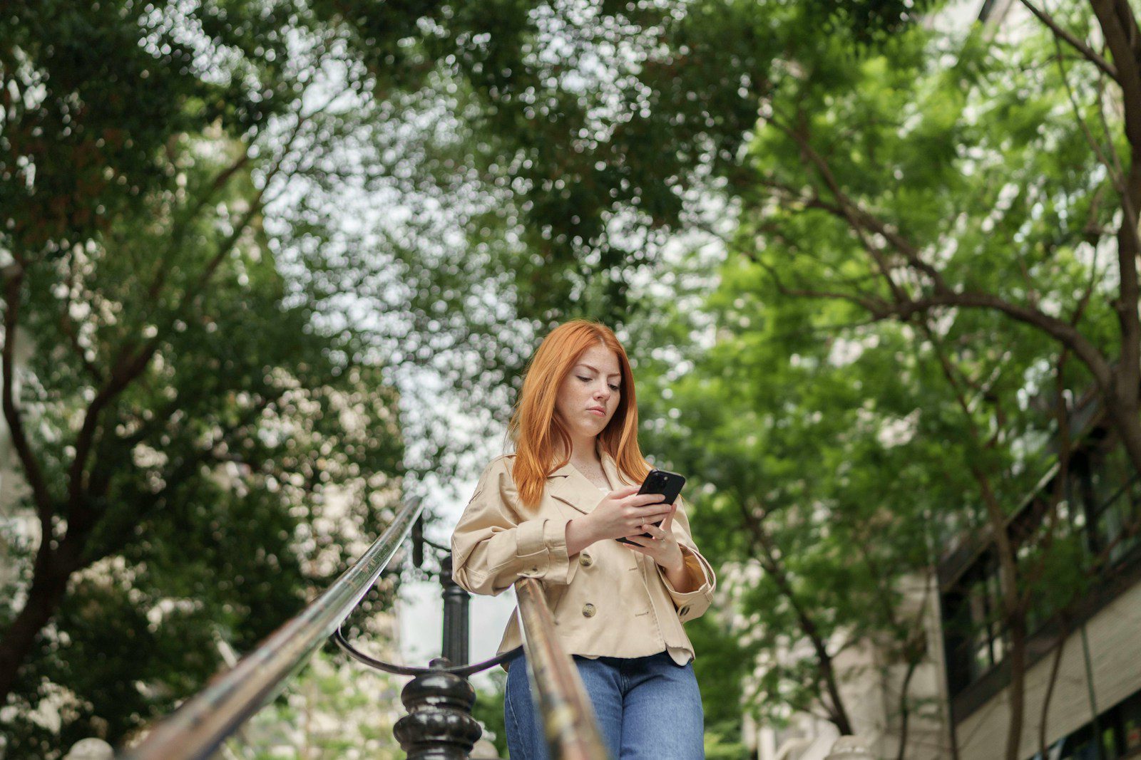 Woman with red hair using a smartphone outdoors.