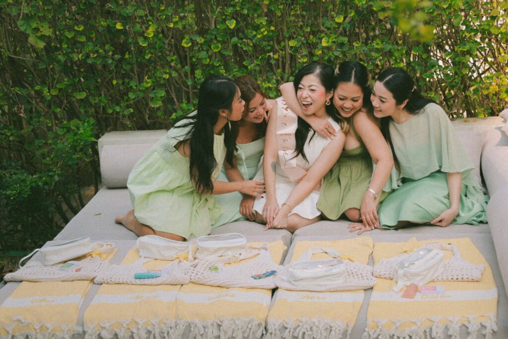 Women in light green dresses hug a woman in white.