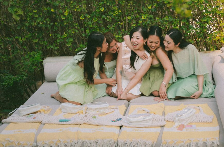 Women in light green dresses hug a woman in white.