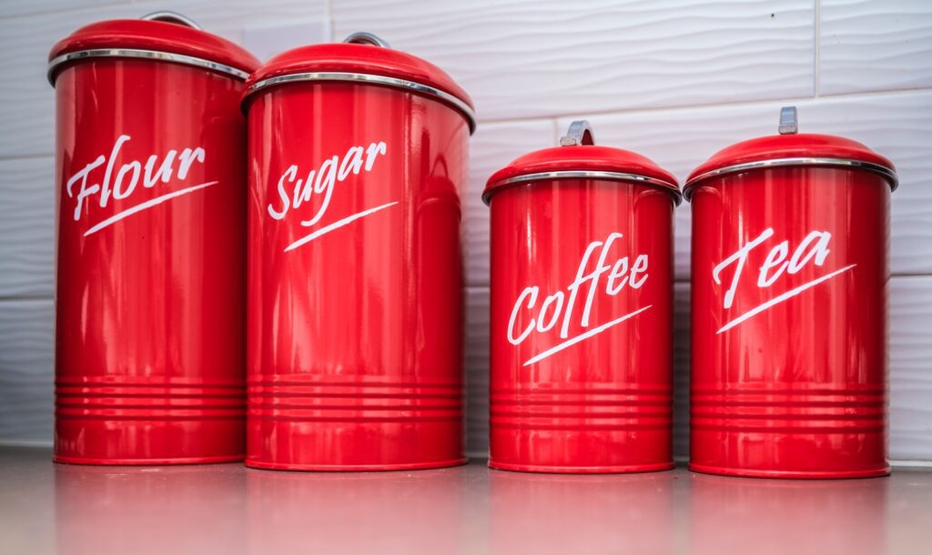 Four red retro canisters labeled flour, sugar, coffee, tea