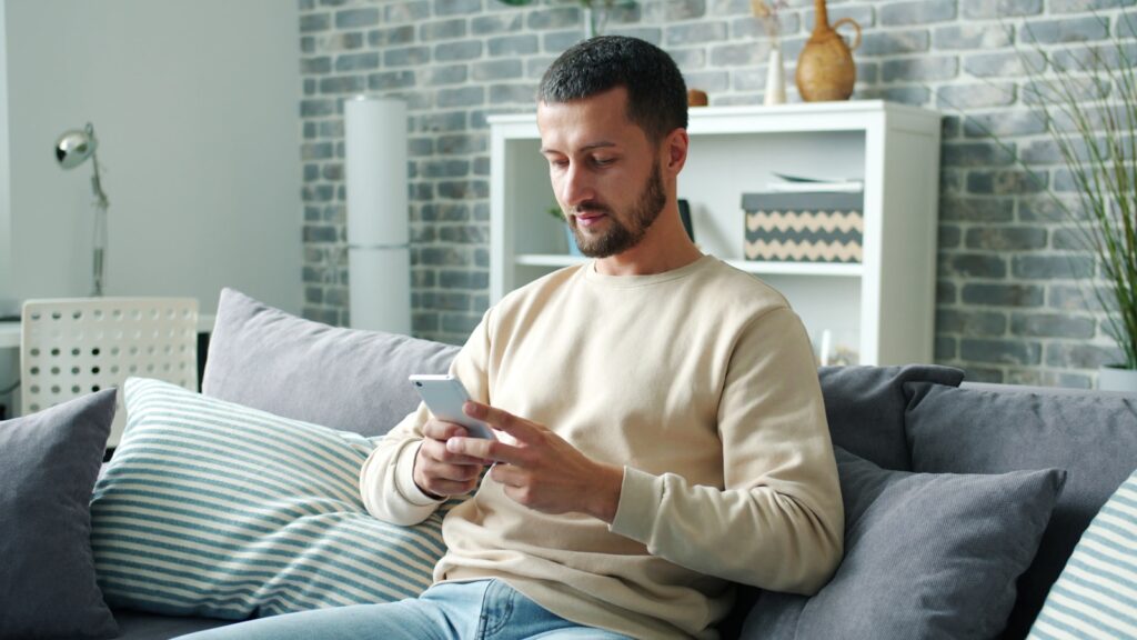 Man sitting on sofa using smartphone