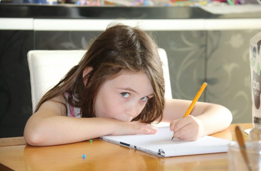 girl in pink tank top writing on notebook