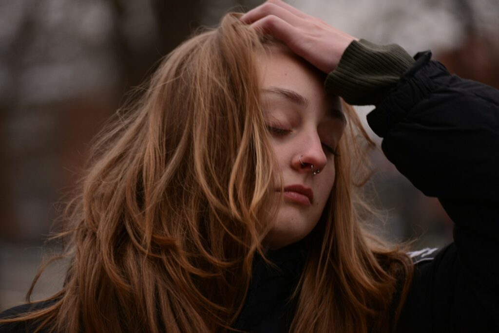 Young woman with auburn hair touching her forehead