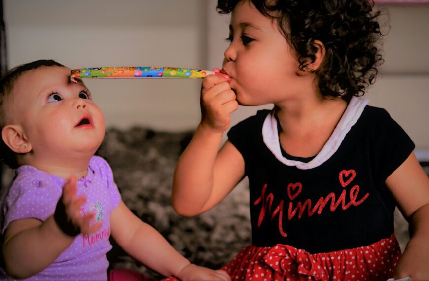 girl in black and red tank top holding pink and green paint brush