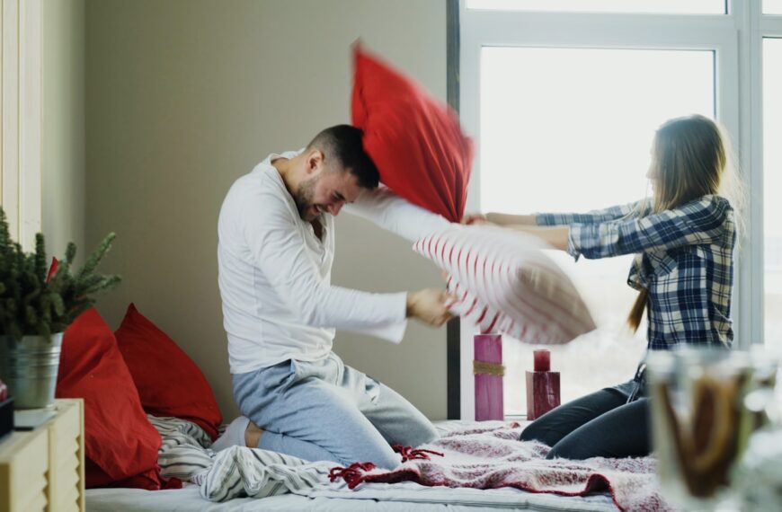 Couple having a playful pillow fight on bed