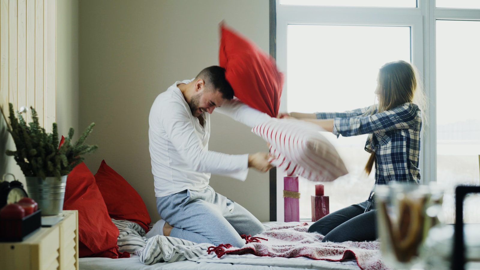 Couple having a playful pillow fight on bed