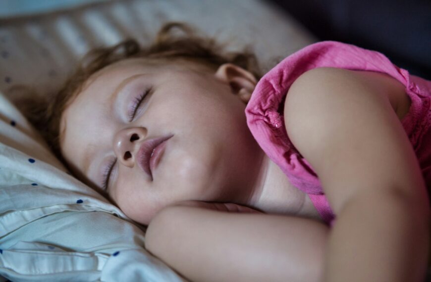 a little girl sleeping on a bed with her eyes closed