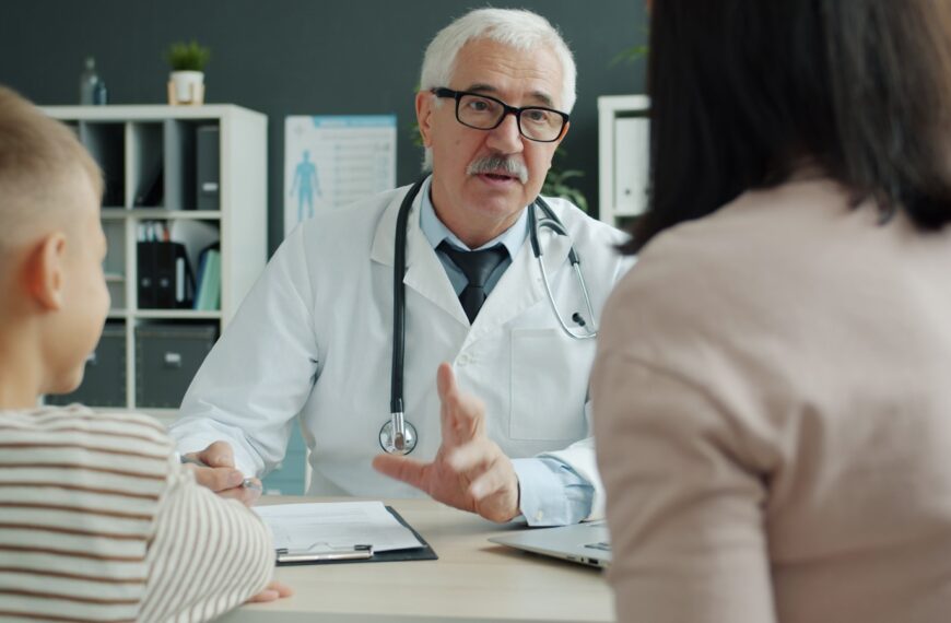 Doctor consults with mother and child in office.