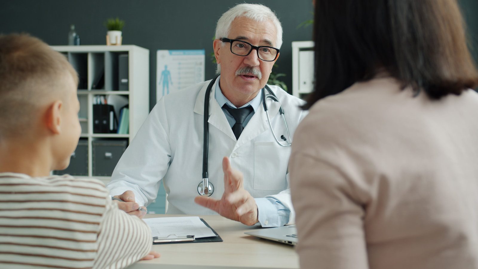 Doctor consults with mother and child in office.