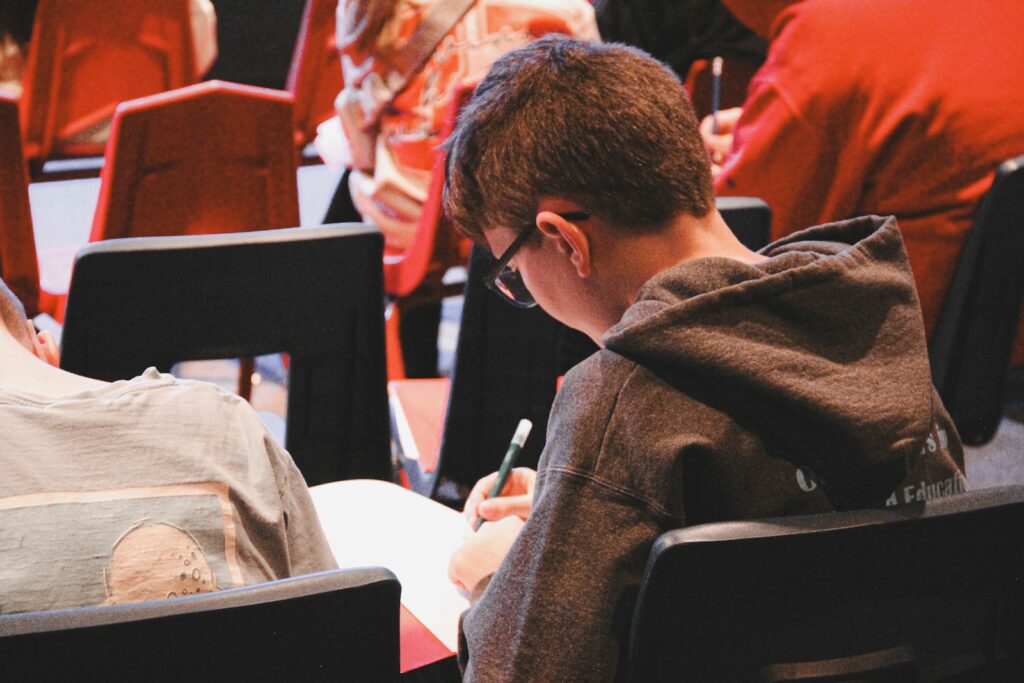 A boy sitting in a chair writing on a piece of paper